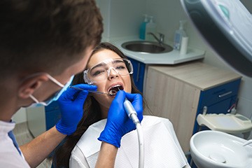 Woman undergoing root canal with dentist in blue gloves