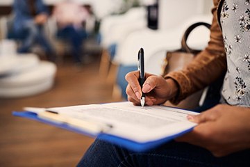 Woman filling out paperwork on a blue clipboard