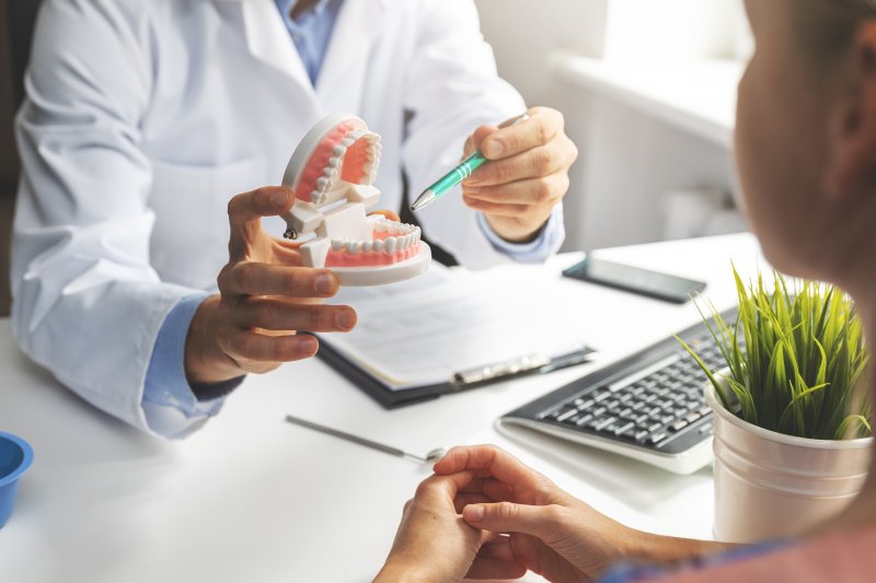 A dentist using a model jaw to explain dental implant treatment