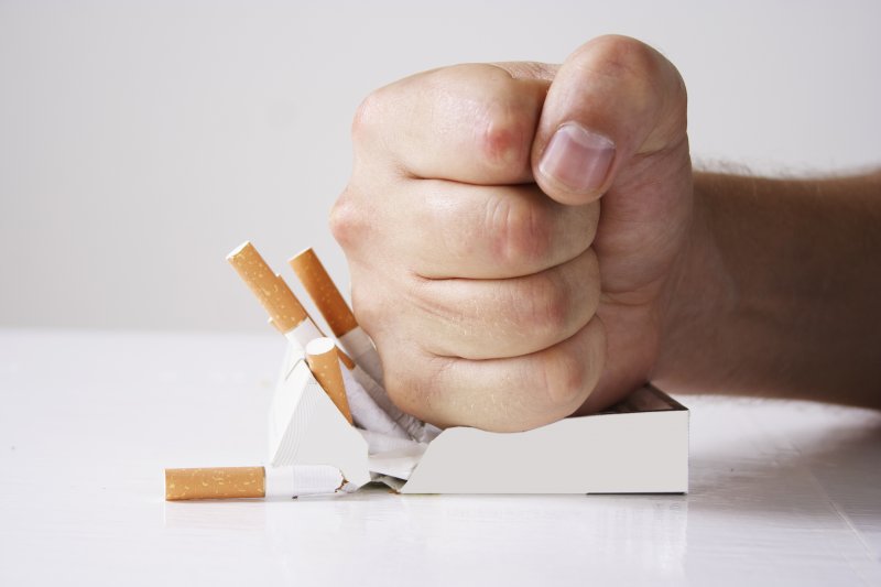 Man crushing a pack of cigarettes